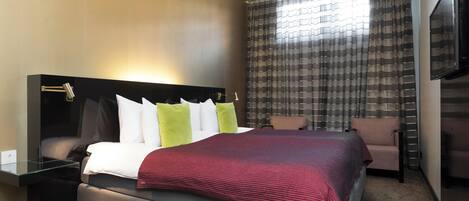 Une chambre d’hôtel avec un grand lit, une table de chevet, une chaise et un téléviseur.