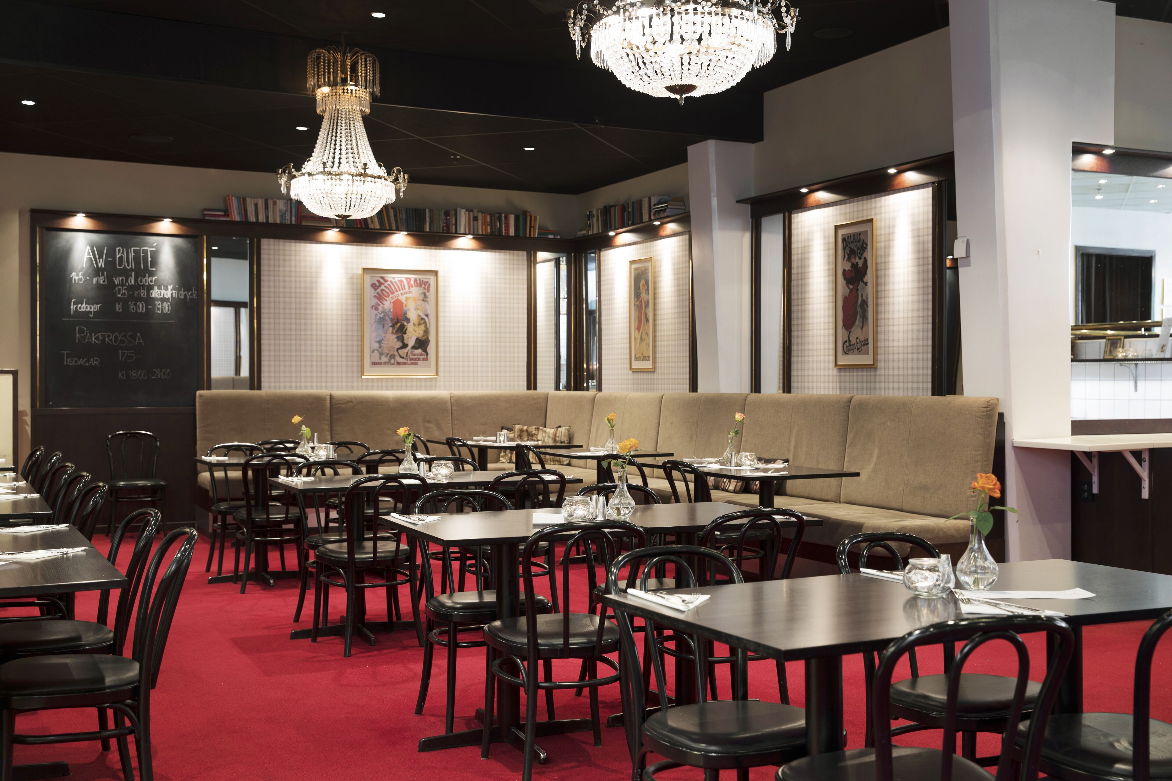 Un restaurante con varias mesas y sillas, una alfombra roja y una araña.