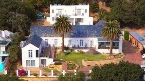 Una casa grande y moderna con piscina, dos palmeras y un jardín bien cuidado.