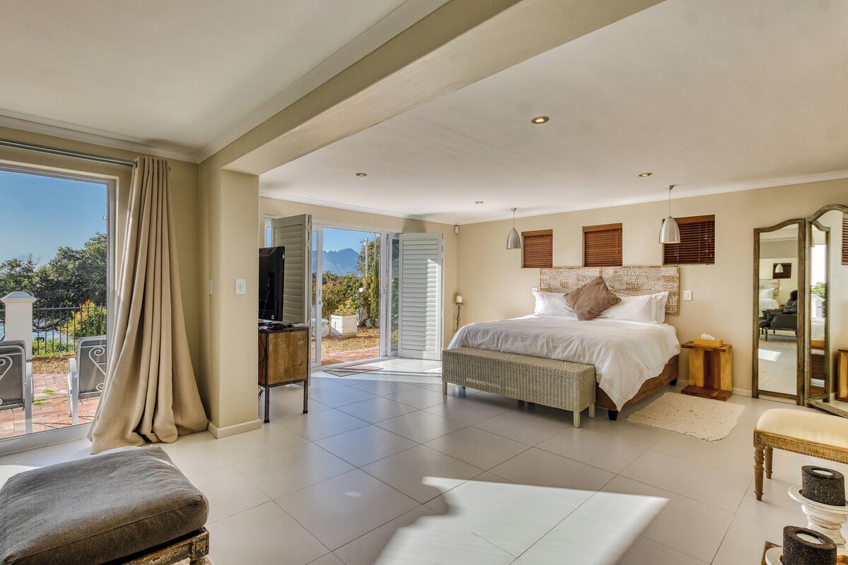 Un dormitorio espacioso con una cama grande, un balcón y vistas al exterior.