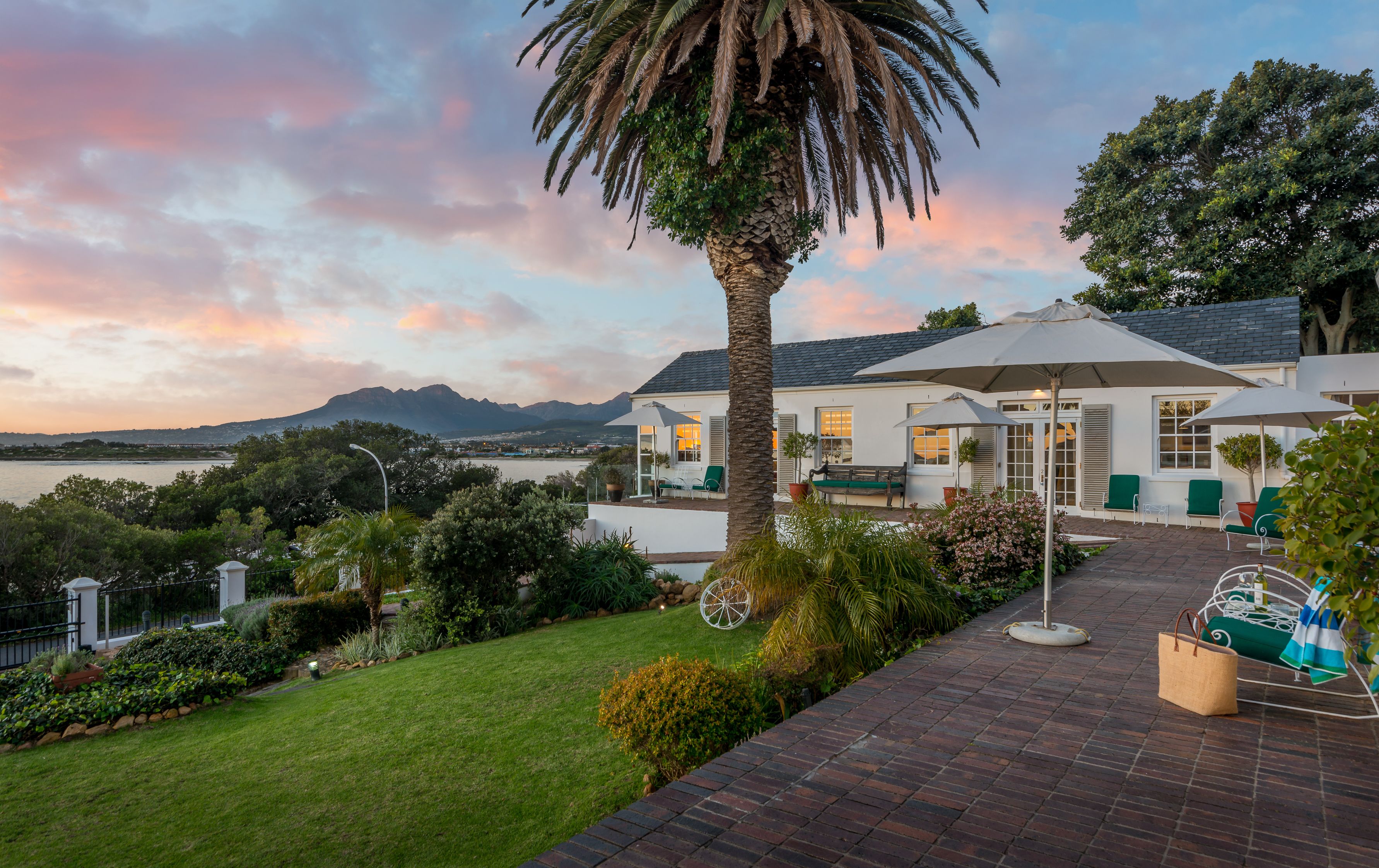 A well-maintained garden with a palm tree, a brick patio, and outdoor seating.