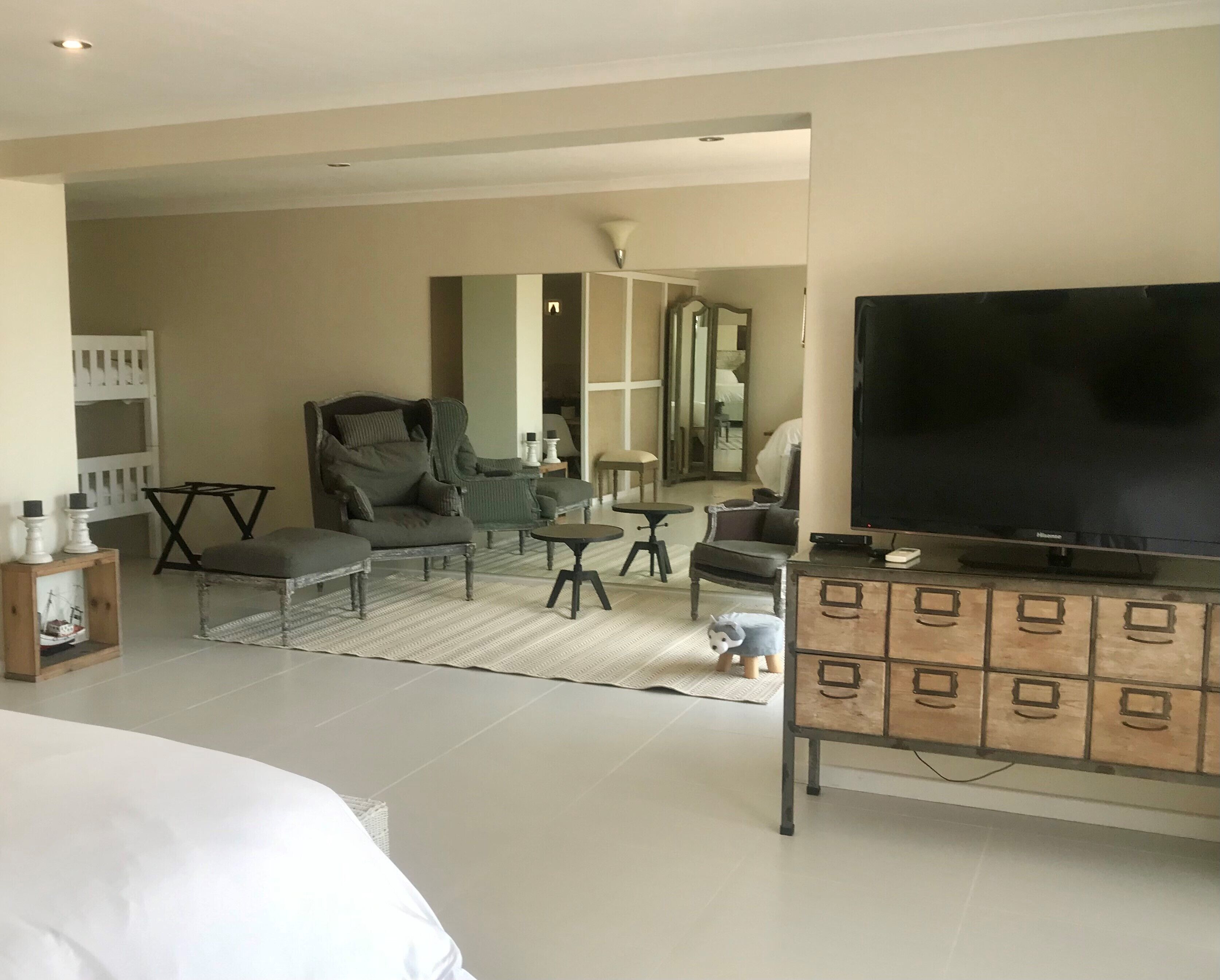 A modern living room with a large TV, comfortable seating, a small table, and a wooden cabinet.