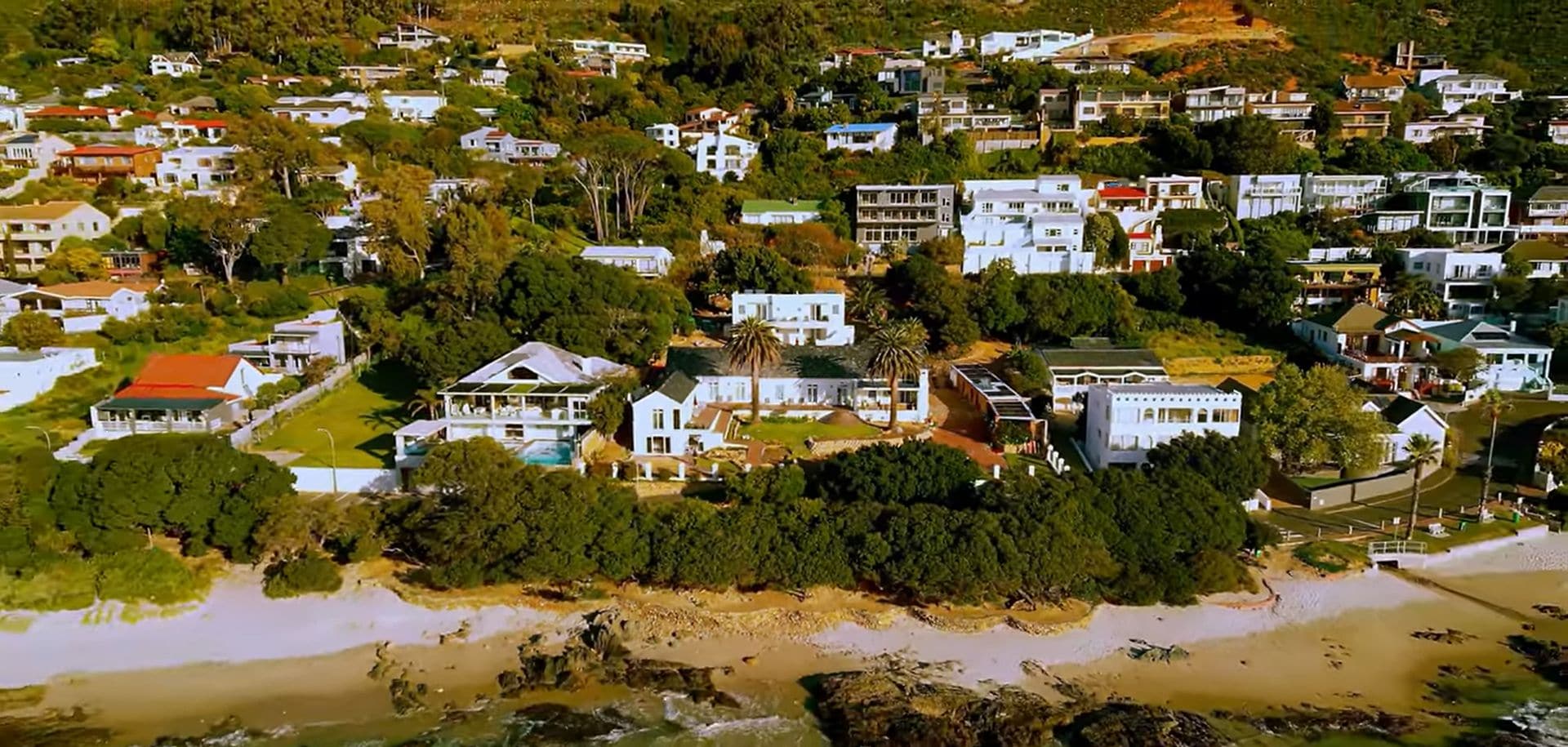 An aerial view of a coastal residential area with houses and a beach.