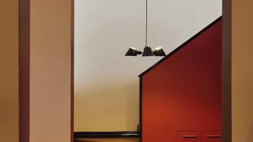 Um interior moderno com uma escada que leva a uma parede vermelha, uma cadeira preta e um lustre pendurado.