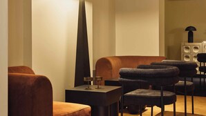 Un salon moderne avec un grand lampadaire, un canapé et un ensemble de fauteuils.