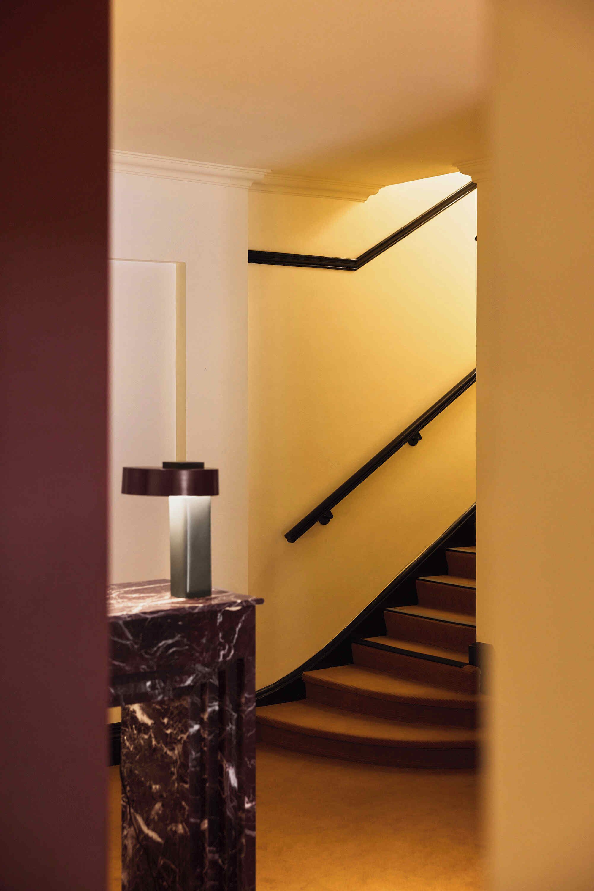 A staircase with a black handrail and beige carpet.