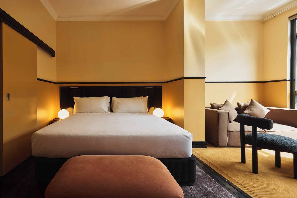 A hotel room with a large bed, a sofa, and a chair.