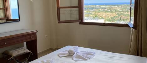 A hotel room with a bed, a desk, a mirror, and a window with a view of the landscape.