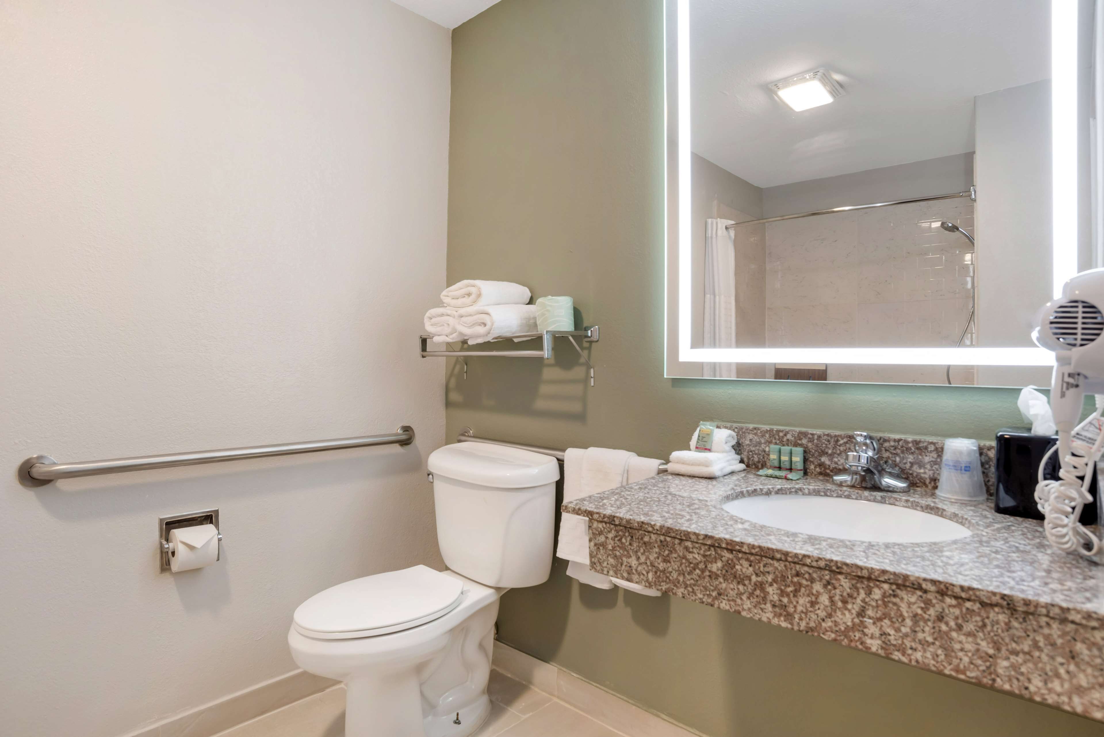 A bathroom with a toilet, sink, and hand dryer.