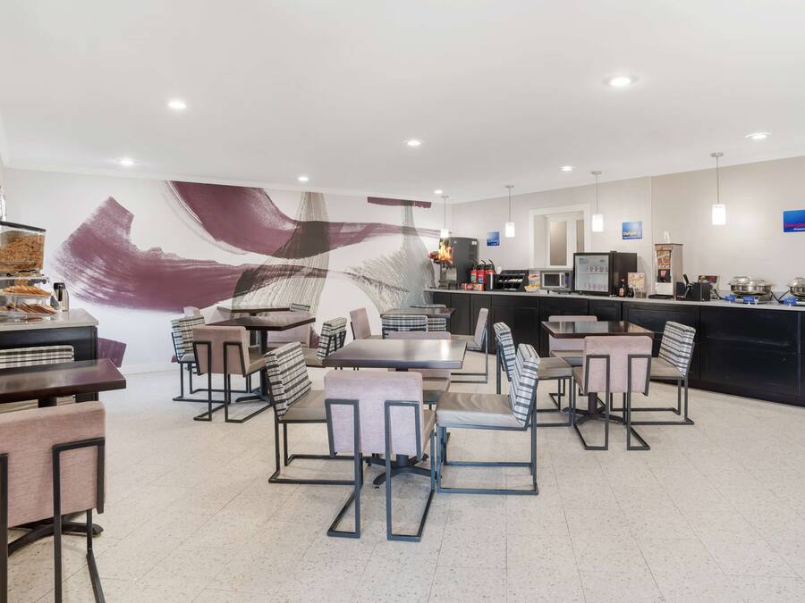 Um restaurante moderno com área de bar, disposição de assentos e um grande mural abstrato na parede.