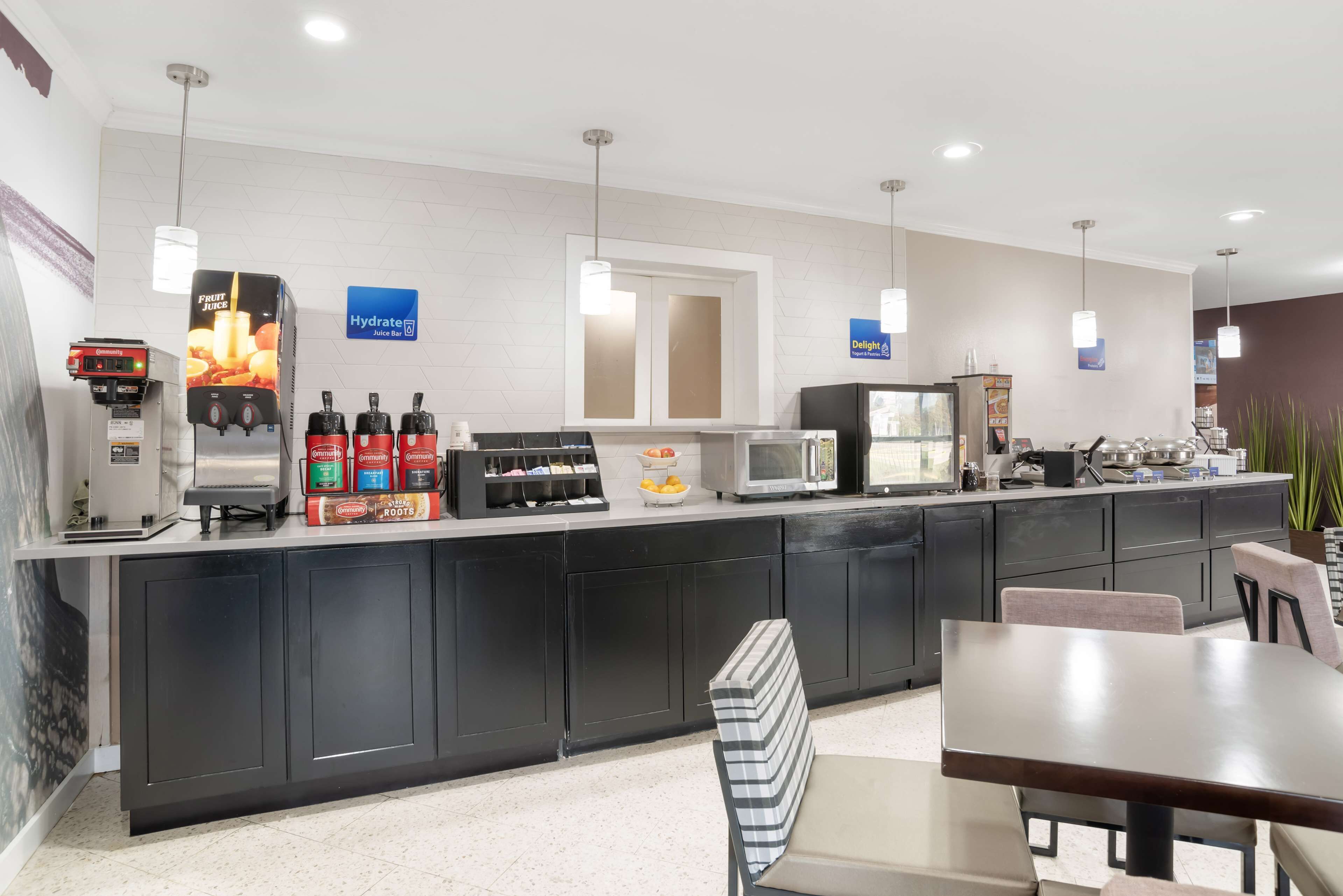 A modern hotel kitchen with a coffee station, microwave, and refrigerator.