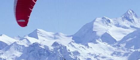A paraglider over snow-covered mountains.