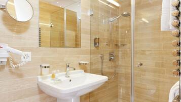 A bathroom with a sink, mirror, and shower.
