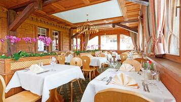 Un ristorante con interni in legno, tovaglie bianche e orchidee viola.