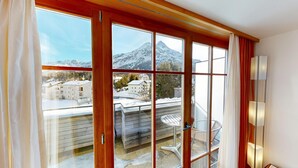 Una habitación con ventanas amplias, un balcón de madera y una silla.
