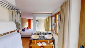 Un baño de hotel moderno con un espejo grande, dos lavamanos y una cama con cabecero de madera.