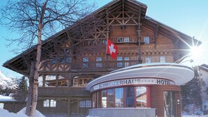 Un edificio de madera con una bandera suiza, un letrero que dice 