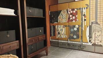 Une pièce dotée d’une armoire en bois, d’un sol carrelé et d’une porte coulissante japonaise traditionnelle ornée de motifs décoratifs.