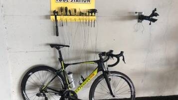 A bicycle leaning against a wall with a yellow sign above it that reads "PEDRO'S TOOL STATION".