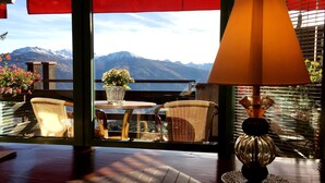 A balcony with wicker chairs, a table with a potted plant, and a lamp. - Hôtel Résidence de la Forêt (Crans-Montana)