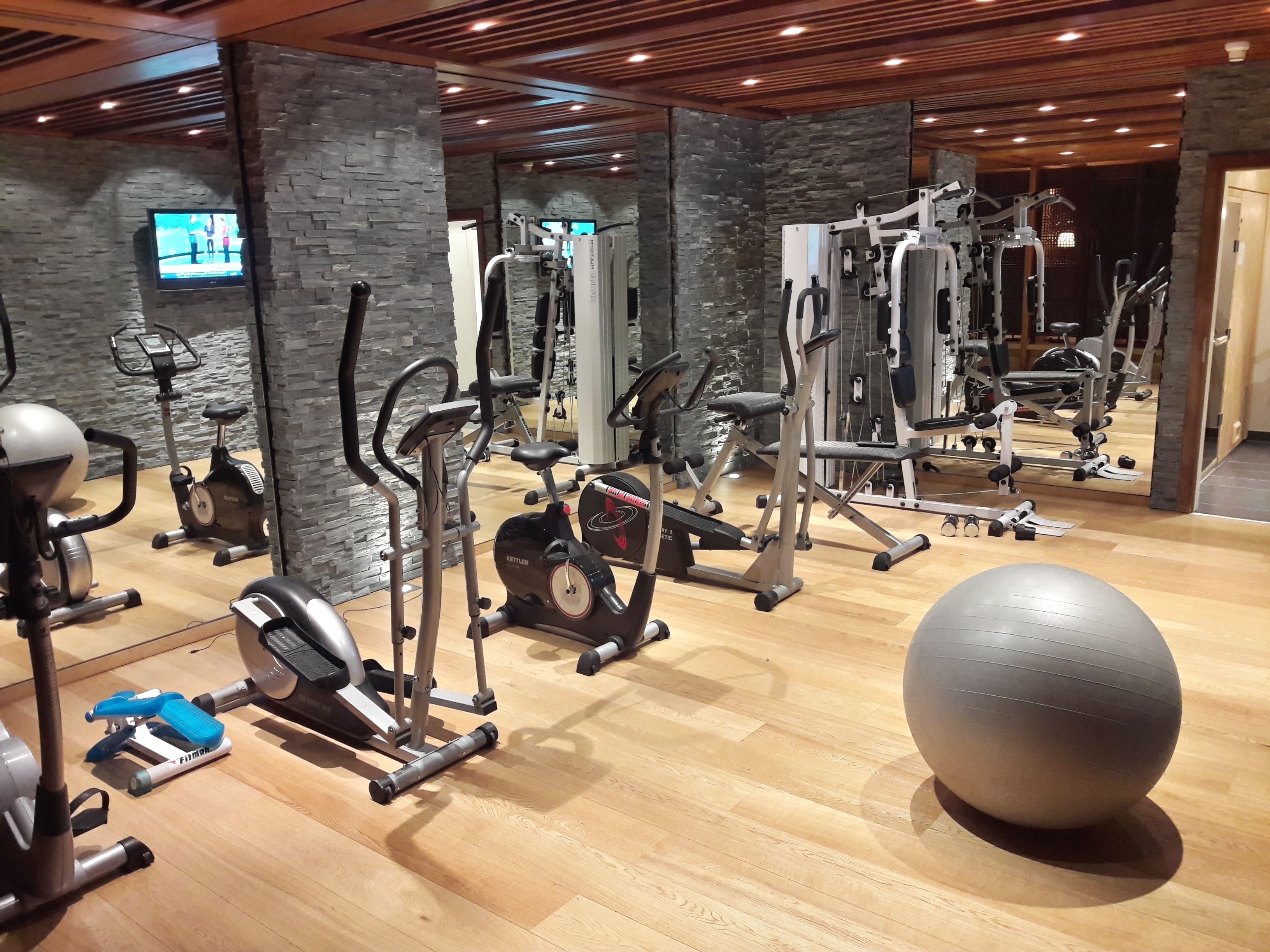 A gym with various exercise equipment, including treadmills, elliptical machines, and weight machines.
