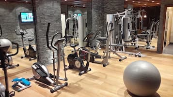 Une salle de sport équipée de divers appareils d’exercice, notamment des tapis de course, des appareils elliptiques et des appareils de musculation.
