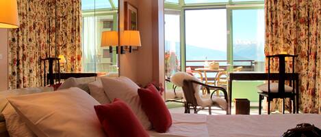 Una habitación de hotel con una cama, dos sillas, una mesa y vistas al exterior.