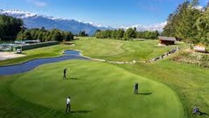 A golf course with a pond, a small building, and a mountainous backdrop. - Hôtel Résidence de la Forêt (Crans-Montana)