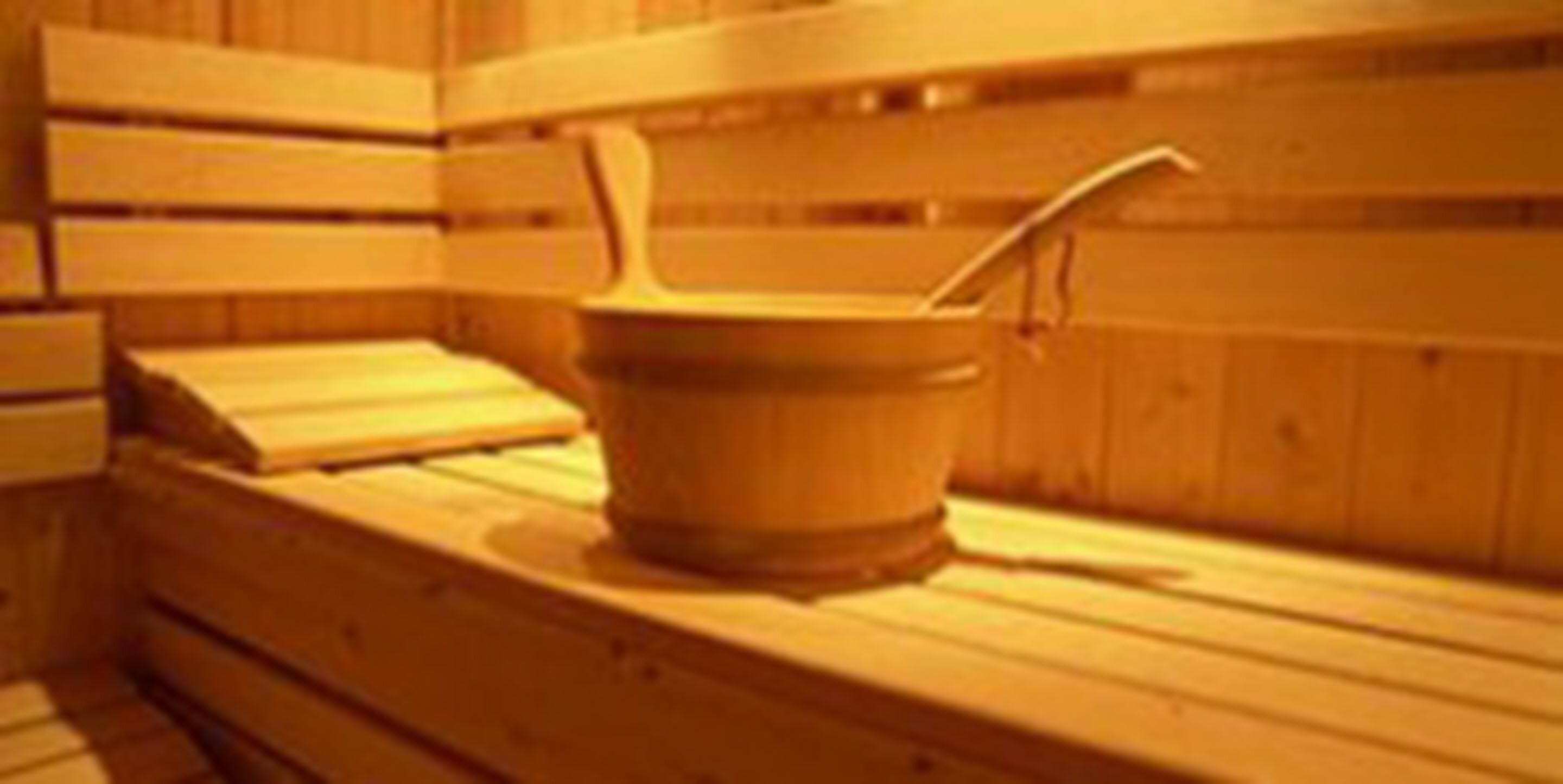 A wooden sauna with benches and a wooden bucket with a ladle.