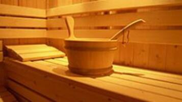 A wooden sauna with benches and a wooden bucket with a ladle.