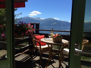 Relax in a serene outdoor space with a breathtaking mountain view, complete with a wicker table, comfortable seating, and a beautiful view of the surrounding landscape.
