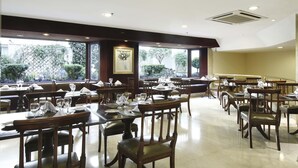 A restaurant with multiple tables and chairs, large windows with a view of greenery, and a ceiling with recessed lighting. - Cyan Americas Towers Hotel (Buenos Aires)