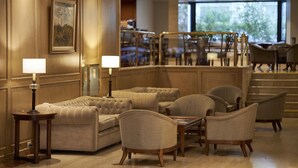 A lobby with a tufted sofa, armchairs, a table with lamps, and a staircase leading to another level. - Cyan Americas Towers Hotel (Buenos Aires)