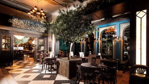 Un restaurante con suelo a cuadros, muebles de madera y un gran árbol como elemento decorativo central.