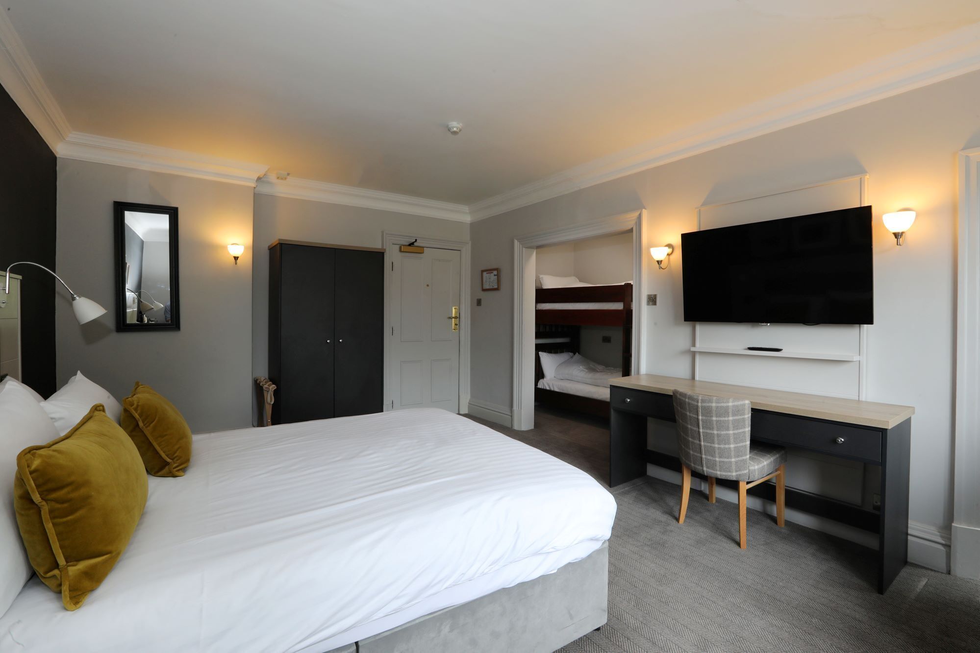 Een hotelkamer met een groot bed, een bureau, een televisie en een kledingkast.
