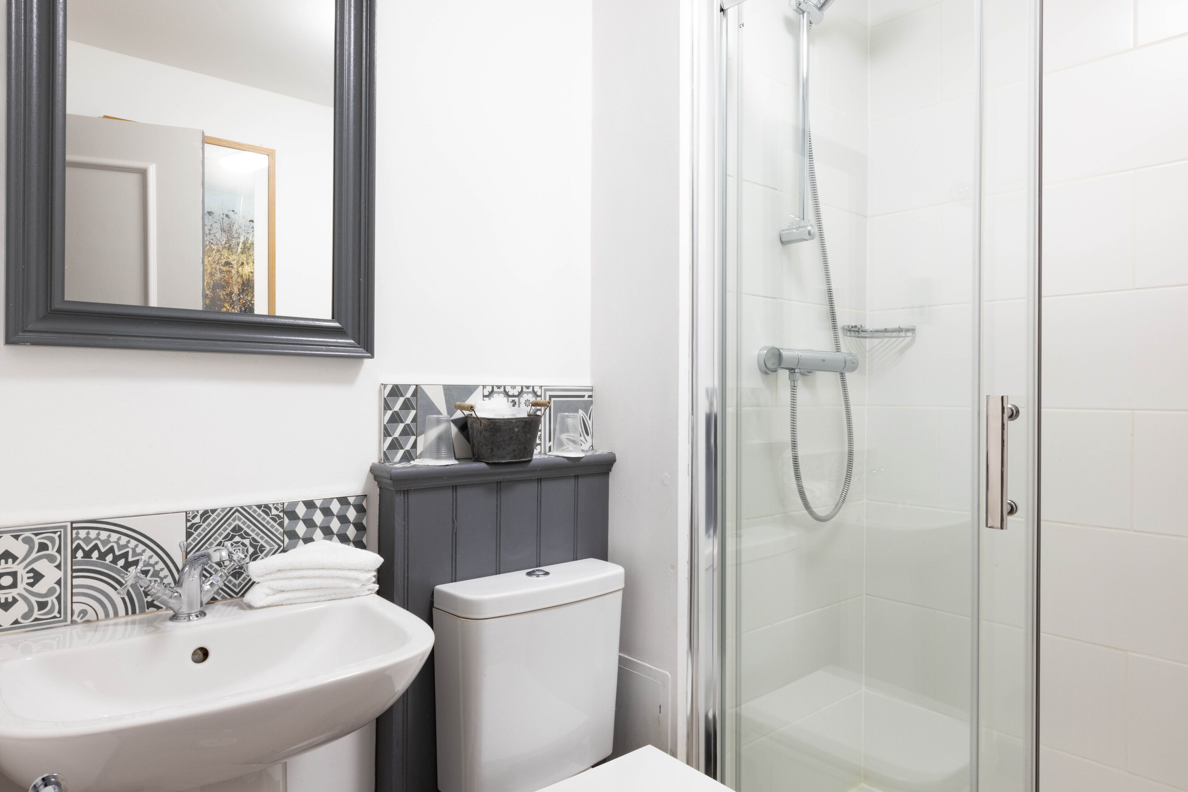 A bathroom with a white sink, a toilet, a shower, and a mirror.