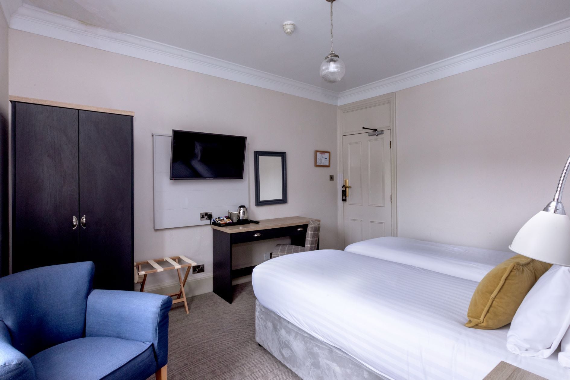Une chambre d’hôtel comprenant un lit, un bureau, une chaise, une télévision et une armoire.