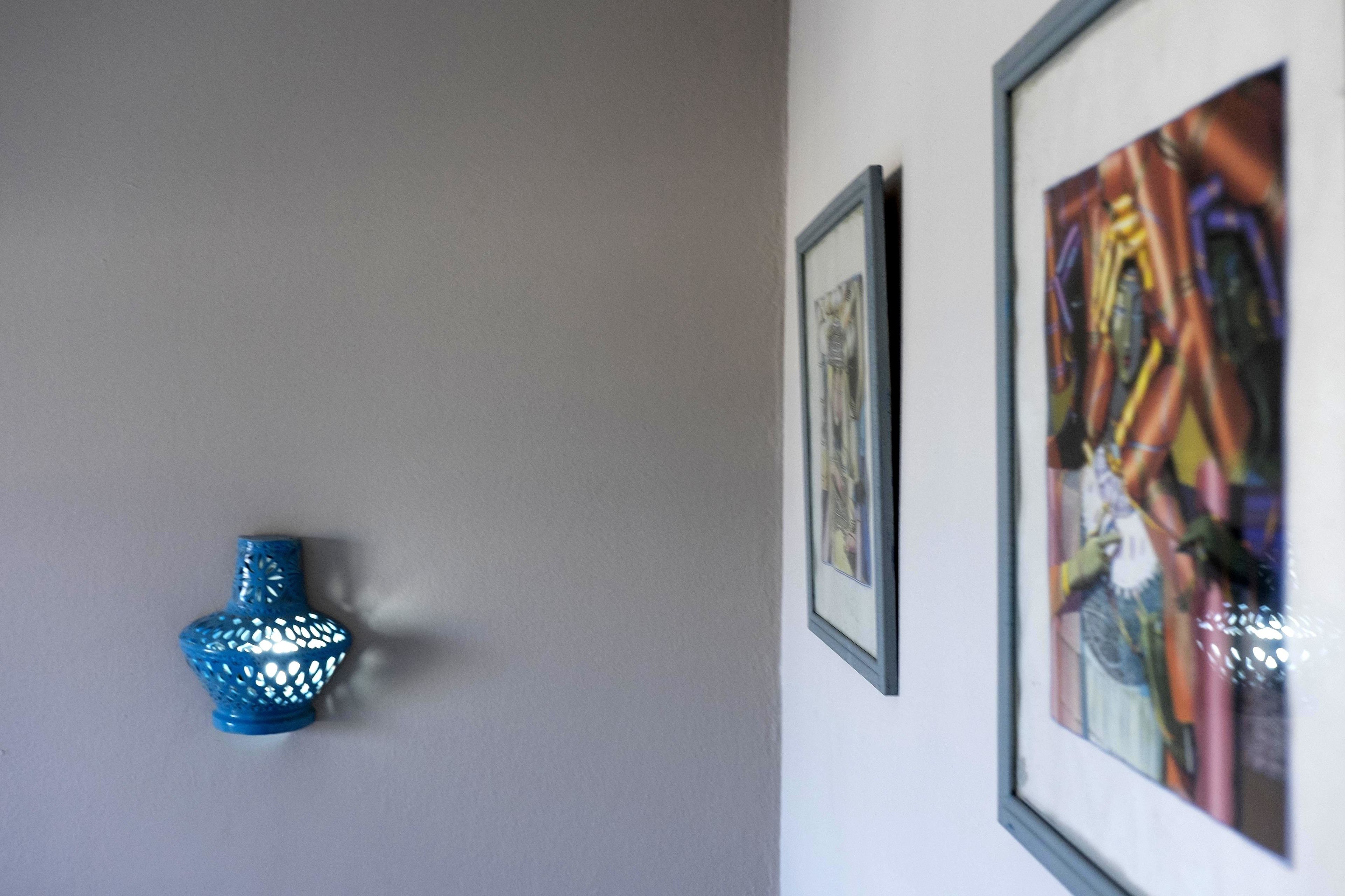 A blue decorative object on a wall, a framed artwork, and a framed picture.
