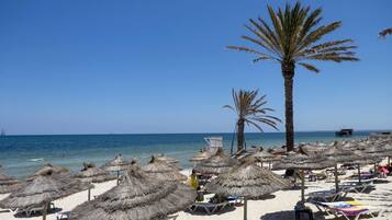 Playa privada, arena blanca, sillas reclinables de playa, sombrillas