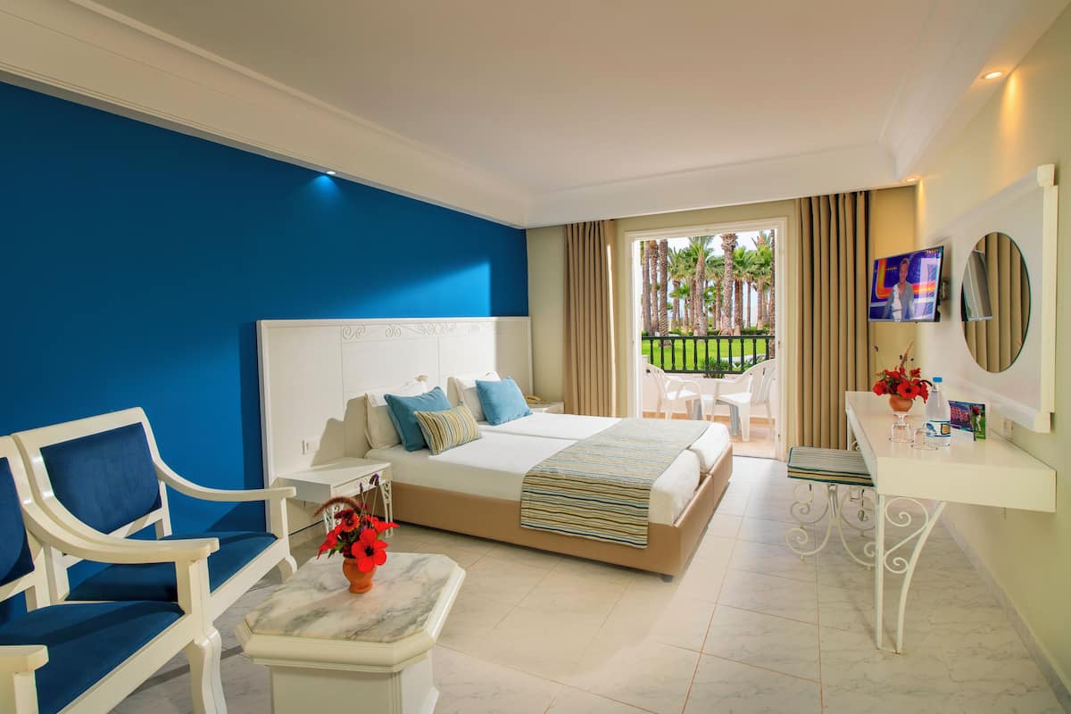 A hotel room with a bed, a desk, a chair, and a view of the outside.
