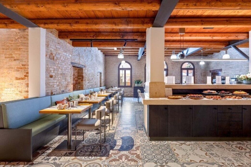 Un restaurante con paredes de ladrillo visto, vigas de madera y una larga barra con comida.