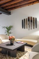Una sala de estar moderna con una mesa de centro de madera oscura, un sofá color beige y una pared decorativa con placas de metal.