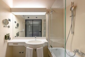 A modern bathroom with a glass-enclosed shower, a white sink, and a mirror.