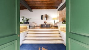 A hotel lobby with a reception desk, seating area, and a staircase leading to the upper floor. - Eurostars Cannaregio (Venice)