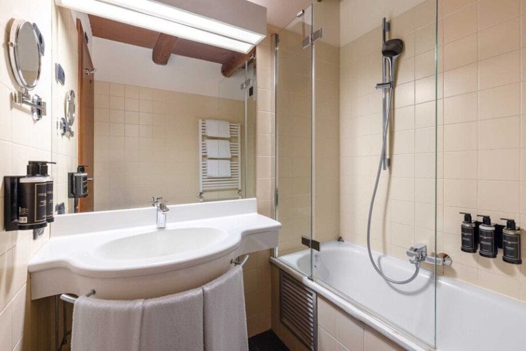 A modern bathroom with a large sink, a glass-enclosed shower, and a towel rack.