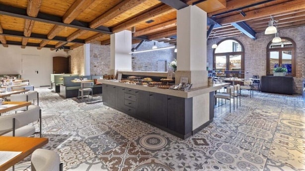 A spacious dining area with a central island, exposed wooden beams, and patterned flooring. - Eurostars Cannaregio (Venice)