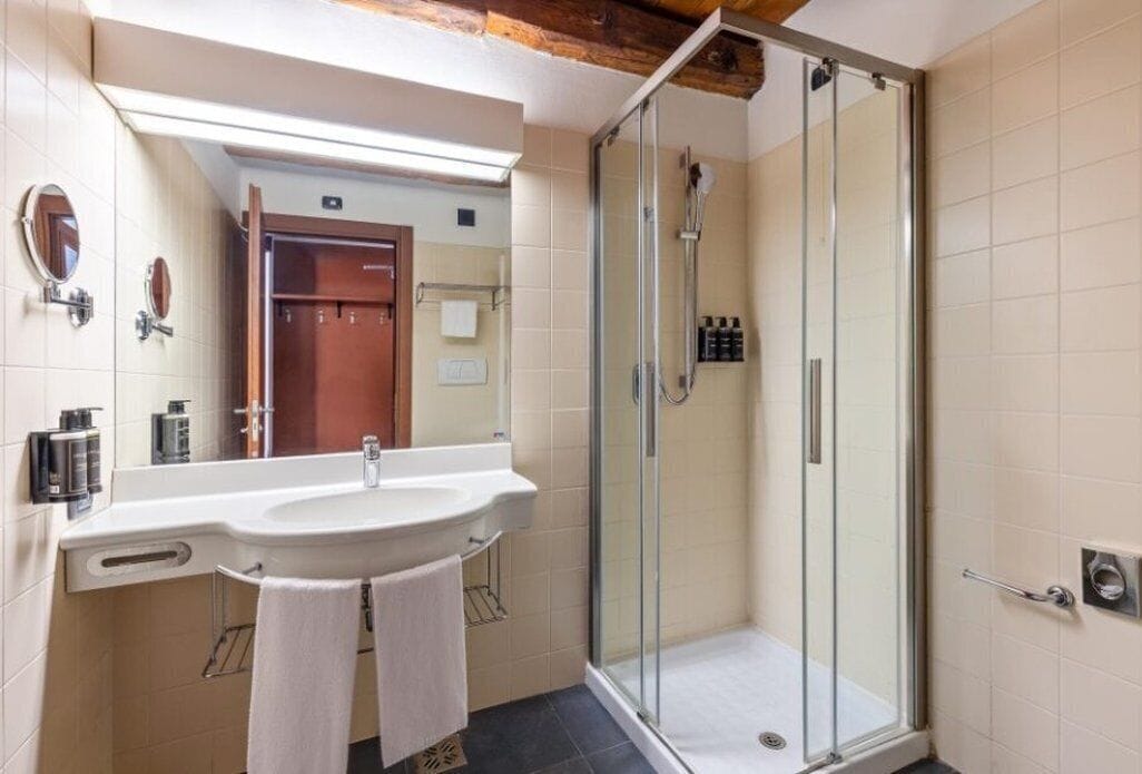 Un baño moderno con cabina de ducha de vidrio, lavabo con espejo y un perchero para toallas.