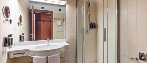 Une salle de bain moderne avec une douche Ă parois de verre, un lavabo avec un miroir et un porte-serviettes.