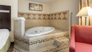 A hotel bathroom with a large bathtub, a bed, and a red chair. - Best Western Parsons Inn (Parsons)