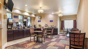 A hotel lobby with a reception desk, a coffee machine, a clock, and a patterned carpet. - Best Western Parsons Inn (Parsons)